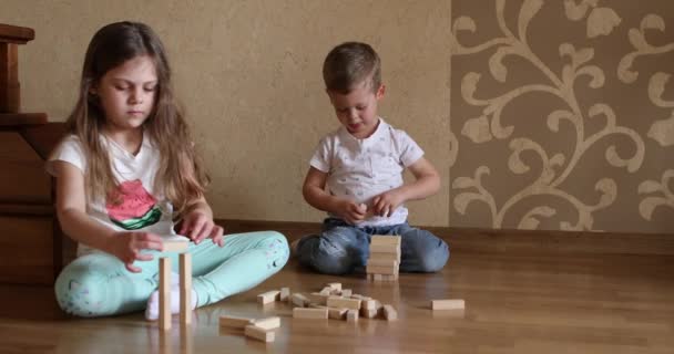 Τα παιδιά παίζουν με ξύλινα τουβλάκια στο πάτωμα του παιδικού δωματίου. — Αρχείο Βίντεο