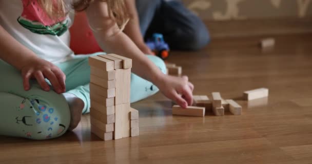 Kinderen spelen met houten blokken op de vloer van de kinderkamer. — Stockvideo