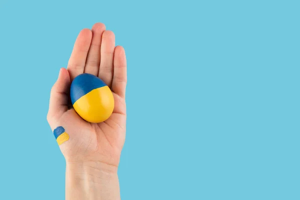 Pasen ei in vrouw hand op Oekraïne vlag kleuren als concept voor oorlog Oekraïne — Stockfoto