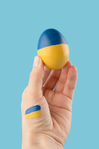 Πασχαλινό αυγό στο χέρι γυναίκα στην Ουκρανία σημαία χρώματα ως έννοια για τον πόλεμο Ουκρανία — Φωτογραφία Αρχείου