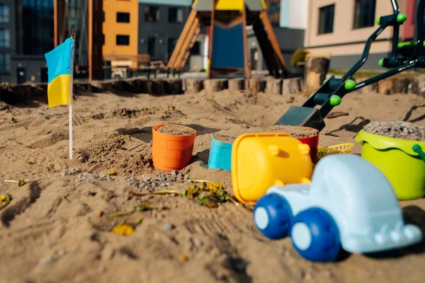 Leksaker i sanden på lekplatsen. Ukrainas flagga — Stockfoto