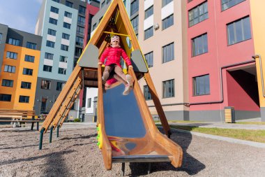 Mutlu kız ve oğlan kaydırağın üzerinde oynuyorlar. Kız çocuk parkında.