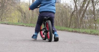 Sonbaharda parkta bisiklet süren bir çocuk.