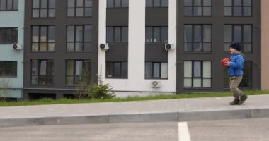 Küçük çocuk sokakta yürüyor.