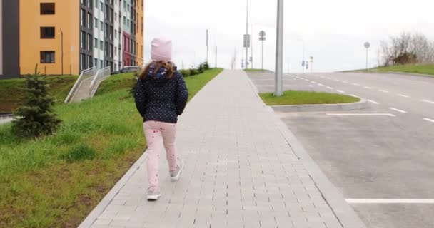 Красива маленька дівчинка, що йде по вулиці — стокове відео