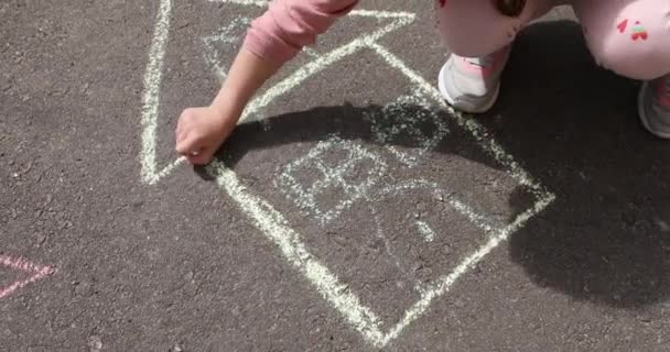 A little girl draws a house with chalk on the pavement. — Stock Video