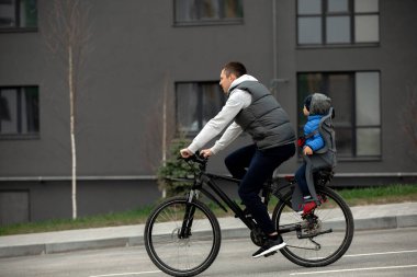 Baba bisikletle oğluyla bisiklet sürüyor.