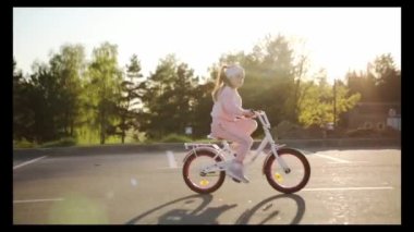 Yaz parkında bisiklet süren küçük bir kız. Dışarıda bisiklete binmek