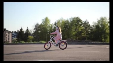 Yaz parkında bisiklet süren küçük bir kız. Dışarıda bisiklete binmek