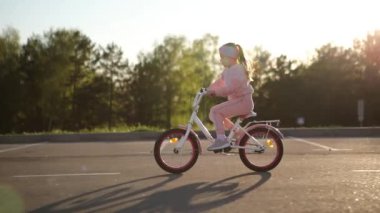 Yaz parkında bisiklet süren küçük bir kız. Dışarıda bisiklete binmek