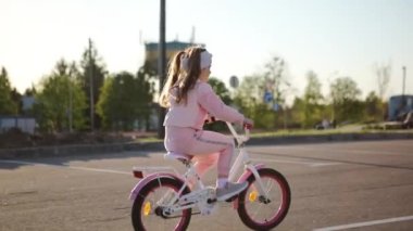Yaz parkında bisiklet süren küçük bir kız. Dışarıda bisiklete binmek