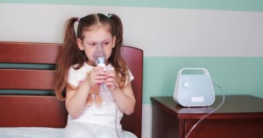 Kız evde nebulizörle solunum yapıyor..