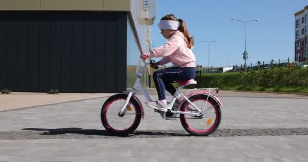 Bambina in bicicletta nel parco in una giornata di sole — Video Stock