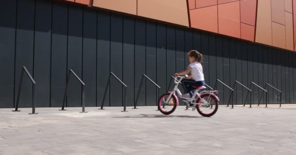 Niña montado en bicicleta en el parque en un día soleado — Vídeos de Stock