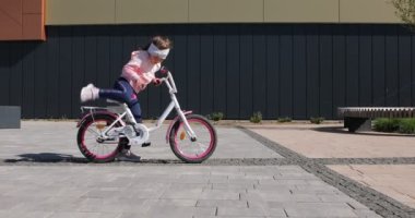 Güneşli bir günde parkta bisiklet süren küçük bir kız.