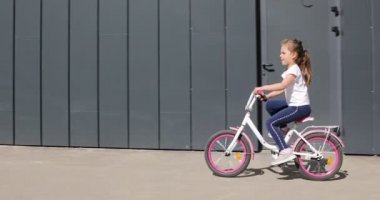 Güneşli bir günde parkta bisiklet süren küçük bir kız.