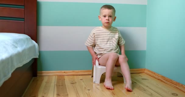 Tuvalette beyaz duvara bakan çocuk doğrudan kameraya bakıyor.. — Stok video