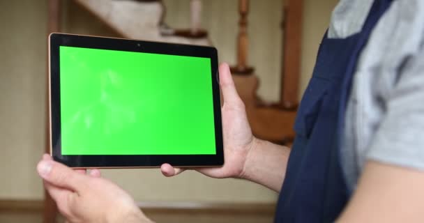 파란 제복을 입은 한 잡역부 가손에 녹색 화면 이 있는 태블릿을 들고 있다. — 비디오