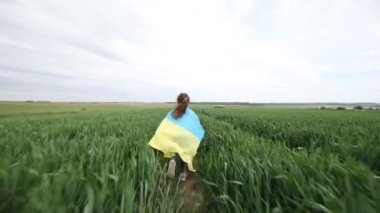 Buğday tarlasında Ukrayna bayrağı taşıyan küçük kız.