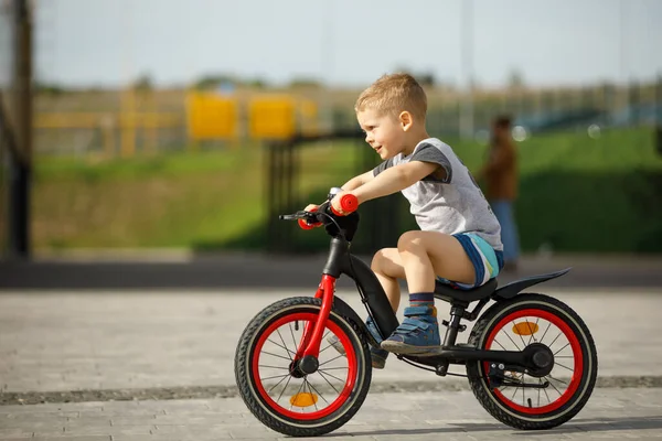 Niño pequeño montando una bicicleta en un parque de la ciudad — Foto de Stock