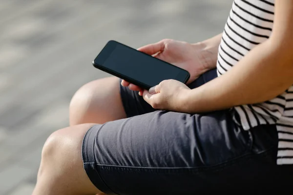 Беременная женщина сидит на скамейке с телефоном — стоковое фото
