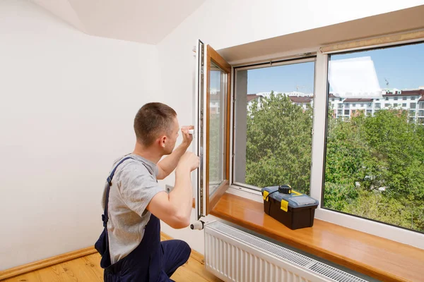 Работник устанавливает и проверяет окно в доме — стоковое фото
