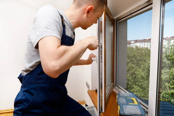 Работник устанавливает и проверяет окно в доме — стоковое фото