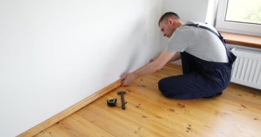 Onarım yapmak için. Yeni bir etek panosu kuruyorum. Bir adam odada tamirat yapar..