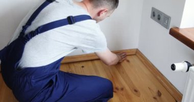 Onarım yapmak için. Yeni bir etek panosu kuruyorum. Bir adam odada tamirat yapar..