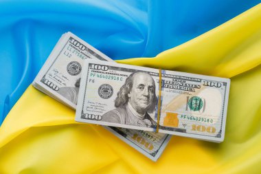 Dolar, Ukrayna bayrağının arka planına karşı. Ukrayna 'daki savaş, tüm dünyadan maddi yardım.