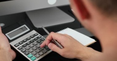 Adam gelir ve giderleri hesaplayan hesap makinesi kullanıyor. Aile bütçesi kavramını yönet.