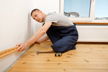 Onarım yapmak için. Yeni bir etek panosu kuruyorum. Bir adam odada tamirat yapar.