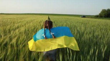 Buğday tarlasında Ukrayna bayrağı taşıyan küçük kız. Bağımsızlık Günü 'nü kutlayan mutlu çocuk..