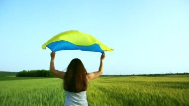 Buğday tarlasında Ukrayna bayrağı taşıyan kız. Bağımsızlık Günü 'nü kutlayan mutlu kız..