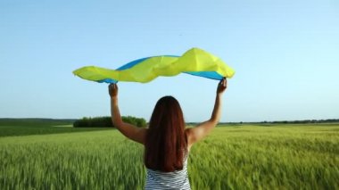 Buğday tarlasında Ukrayna bayrağı taşıyan kız. Bağımsızlık Günü 'nü kutlayan mutlu kız..
