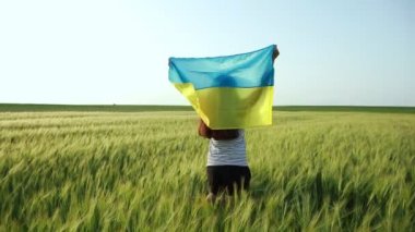 Genç hamile bir kız Ukrayna bayrağıyla neşeyle buğday tarlasında koşuyor.. 