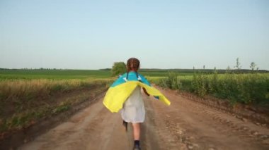 Kız neşeyle Ukrayna bayrağıyla buğday tarlasında koşuyor.. 
