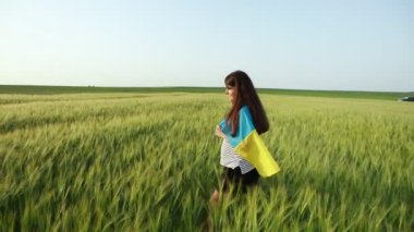 Genç hamile bir kız Ukrayna bayrağıyla neşeyle buğday tarlasında koşuyor.. 