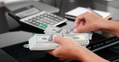 Kadın eli, 100 dolarlık banknotları da sayıyor. Yatırım, para değişimi, rüşvet veya yolsuzluk kavramı.