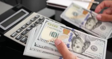 Kadın eli, 100 dolarlık banknotları da sayıyor. Yatırım, para değişimi, rüşvet veya yolsuzluk kavramı.