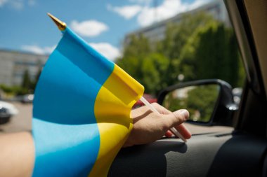 Bir adam arabada otururken Ukrayna bayrağını tutuyor. Bir Avrupa ülkesinin bağımsızlığının sembolü. Milliyetçilik, vatanseverlik, özgürlük kavramı.