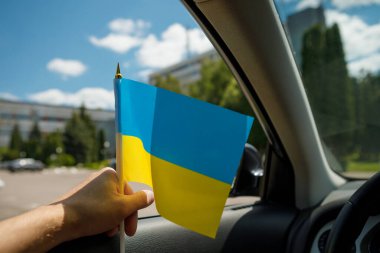 Bir adam arabada otururken Ukrayna bayrağını tutuyor. Bir Avrupa ülkesinin bağımsızlığının sembolü. Milliyetçilik, vatanseverlik, özgürlük kavramı.
