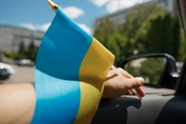 Bir adam arabada otururken Ukrayna bayrağını tutuyor. Bir Avrupa ülkesinin bağımsızlığının sembolü. Milliyetçilik, vatanseverlik, özgürlük kavramı.