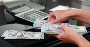 Kadın eli, 100 dolarlık banknotları da sayıyor. Yatırım, para değişimi, rüşvet veya yolsuzluk kavramı.