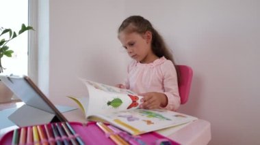 Uzaktan öğrenme çevrimiçi eğitim. Kız evde dijital tablet dizüstü bilgisayarla ders çalışıyor ve ödev yapıyor..