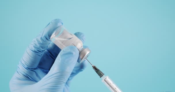 青い医療用手袋の手は バイアルからワクチンで注射器を描きます コロナウイルスワクチンの概念 — ストック動画