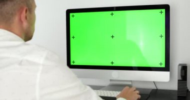 Yeşil ekran. Bilgisayarda çalışan bir çalışan masasında oturuyor. Arkadan bak. Yüksek kalite 4k görüntü