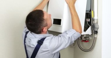 Tesisatçı konut ısıtma sorununu çözmeye çalışıyor. Gaz kazanı tamiri