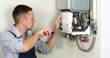 A plumber is attempting to fix a residential heating problem. Gas boiler repair