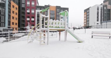 Child on winter playground. A little child play on the slide on the winter snow covered playground. 